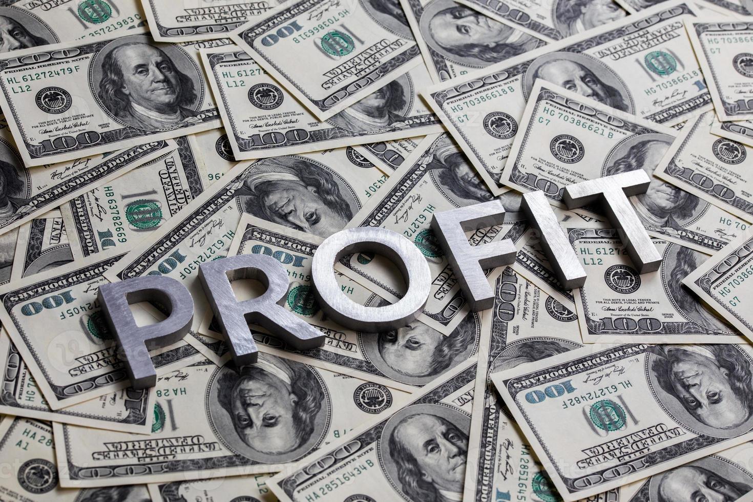 The word PROFIT laid with aluminium letters on the US dollar banknotes background - with selective focus photo