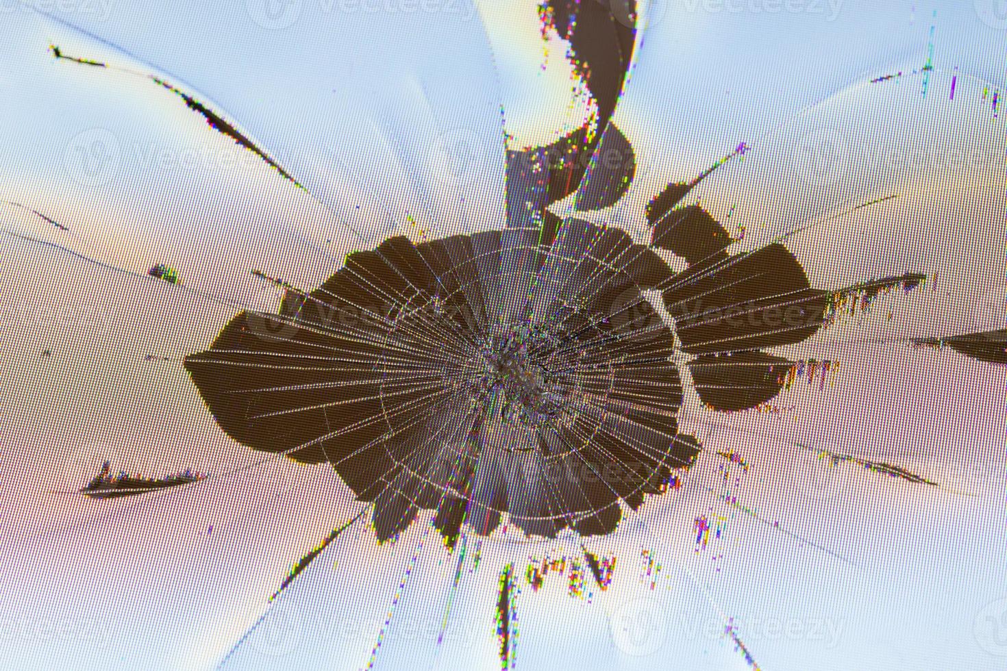 close-up view of physically damaged lcd screen surface with impact spot, radial cracks, pixel grid leakage and discoloration photo