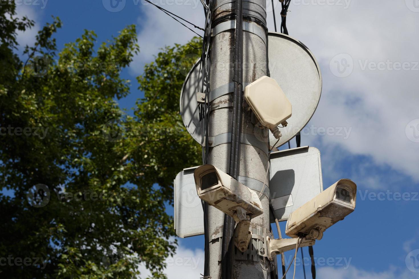 dos viejas cámaras de vigilancia de seguridad cctv en el poste de luz de la calle sobre fondo de cielo azul foto