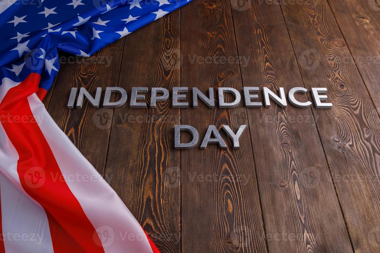 the words independence day laid on brown wooden planks surface with crumpled united states of america flag photo