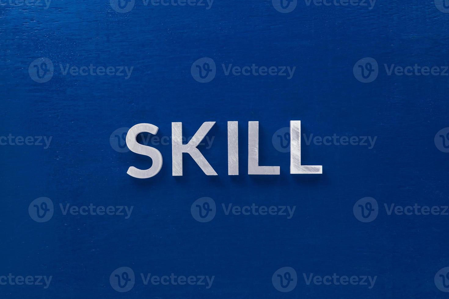 the word skill laid with silver metal letters on classic blue board in flat lay with central composition photo