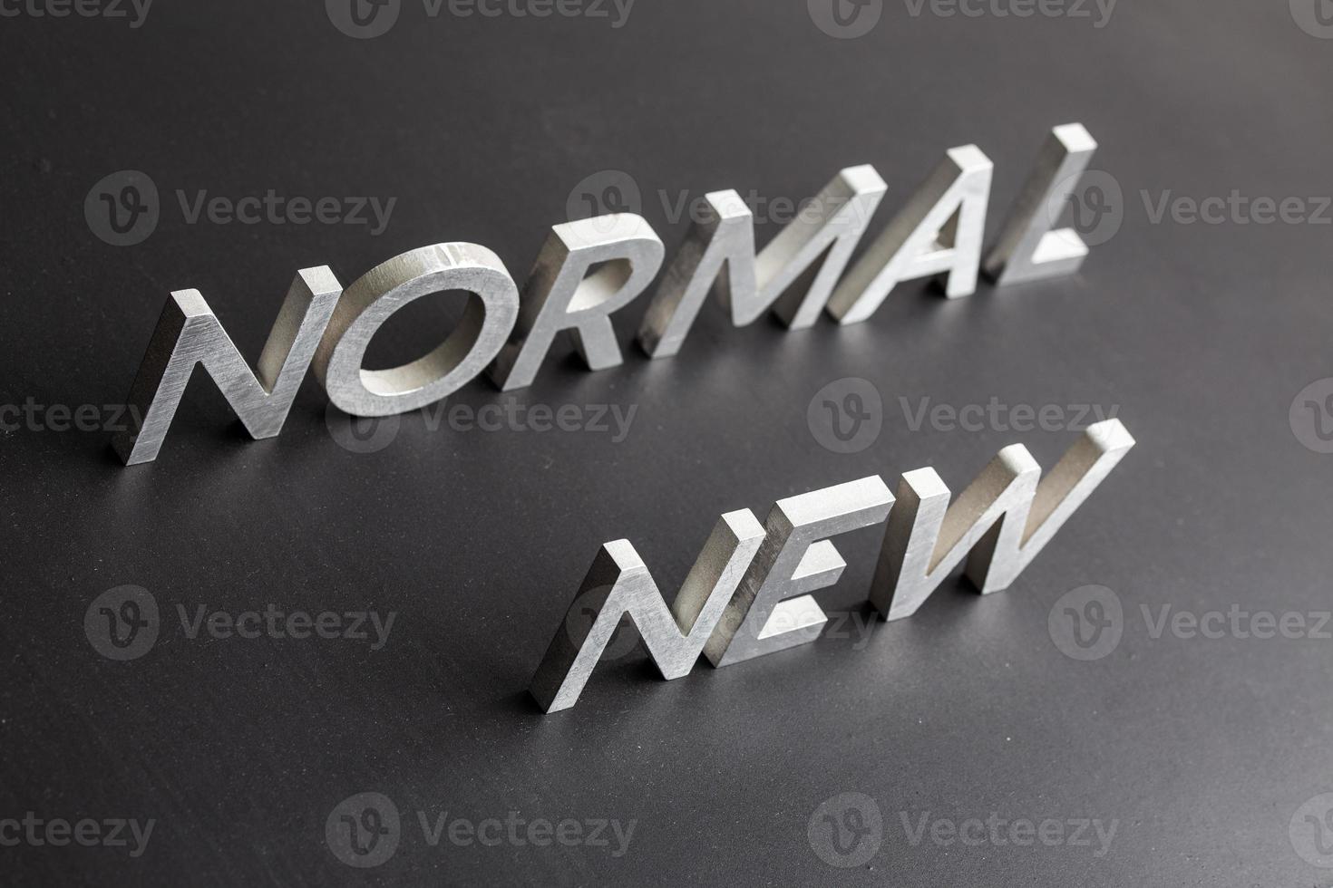 new normal word composed of silver metal letters on a flat matt black surface with diagonal perspective photo