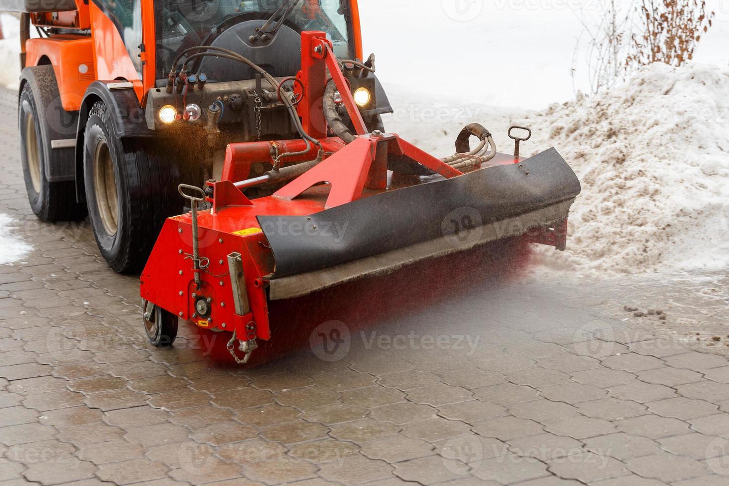 Snow cleaning. Snow removal tractor clearing snow from pavement with special round spinning brush, photo