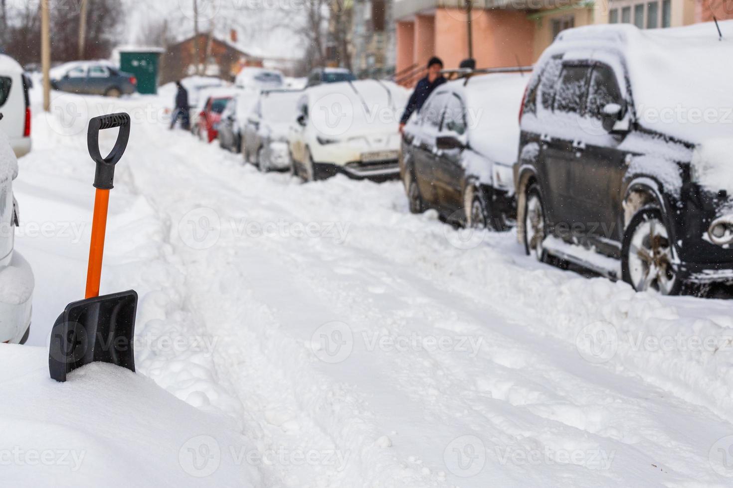 small plastic snow shovel near snow-covered cars at sunny winter morning photo