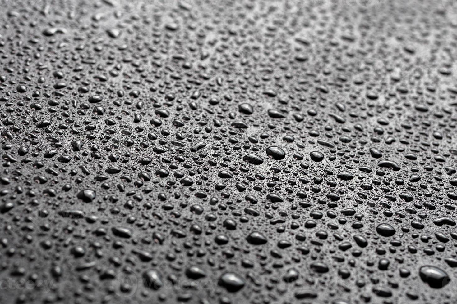 water drops on abstract flat black hydrophobic surface macro background with selective focus photo