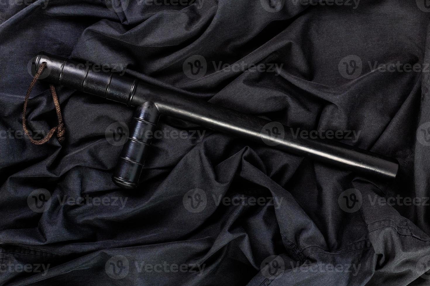 black rubber police baton on black shirt wrinkled cloth low-key flat lay photo