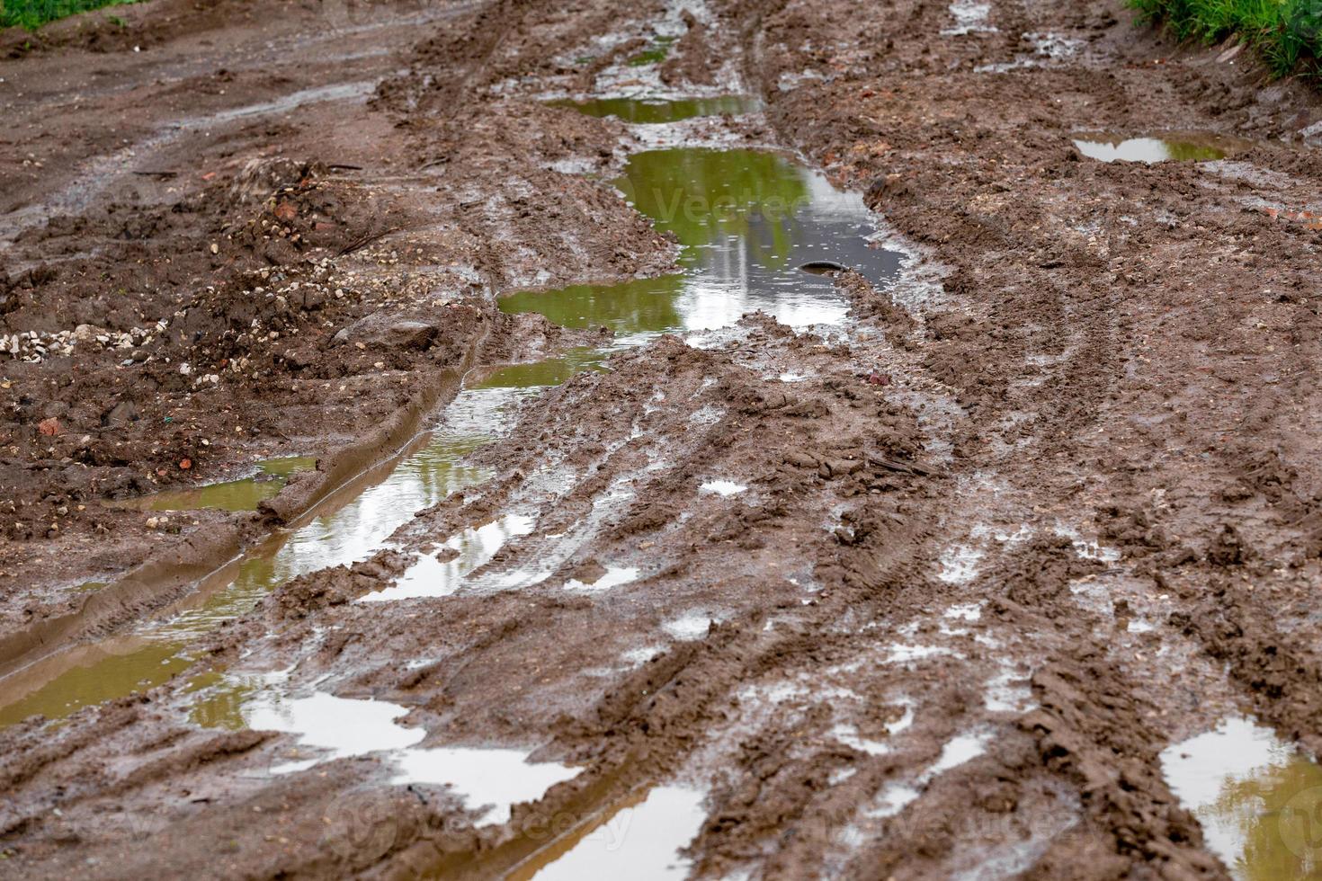 dirty clay mud crossroads with puddles and tire tracks - close-up with selective focus and linear perspective photo