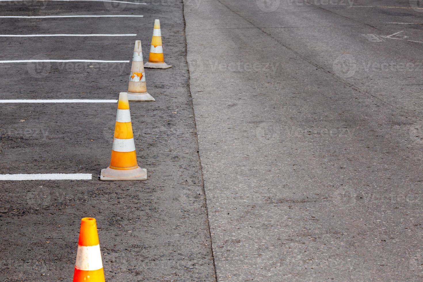 Orange road cones on a asphelt driving area with white lines photo