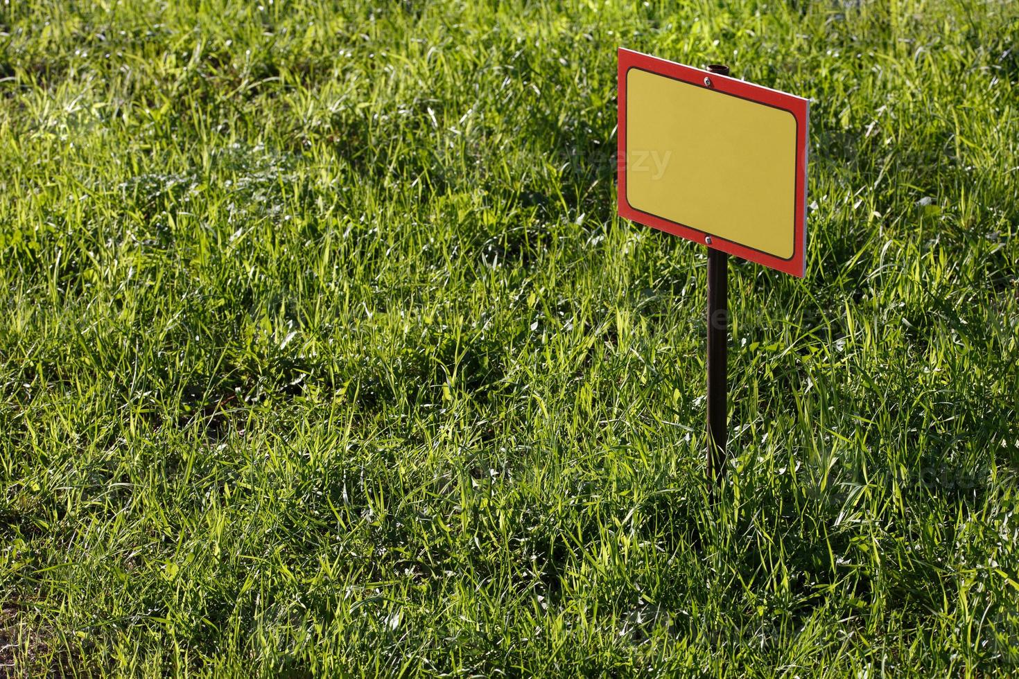 blank yellow sign mockup on green lawn background - close-up with selective focus photo