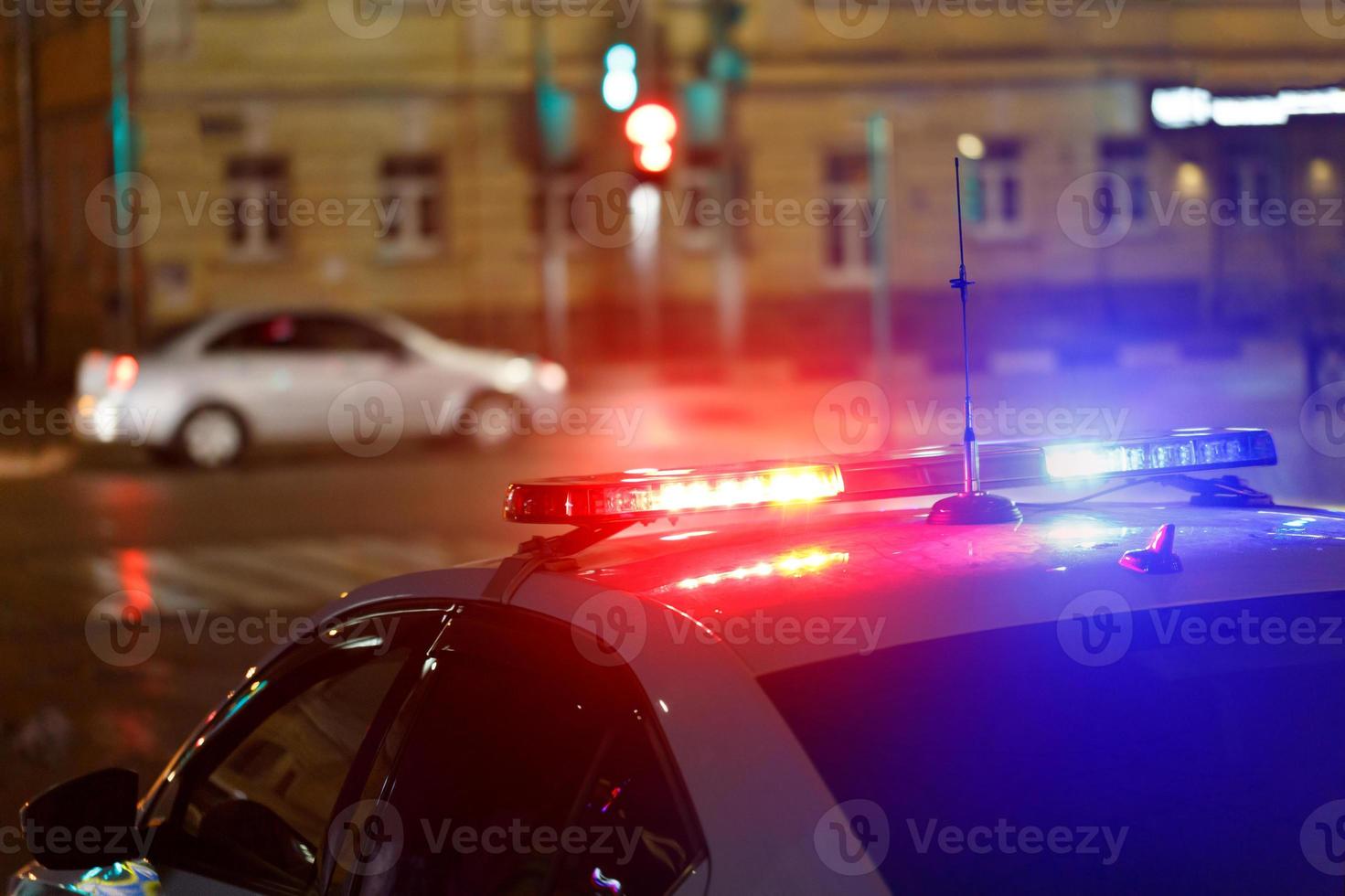 luces de coche de policía nocturnas en la calle de la ciudad con coche civil en un fondo borroso foto