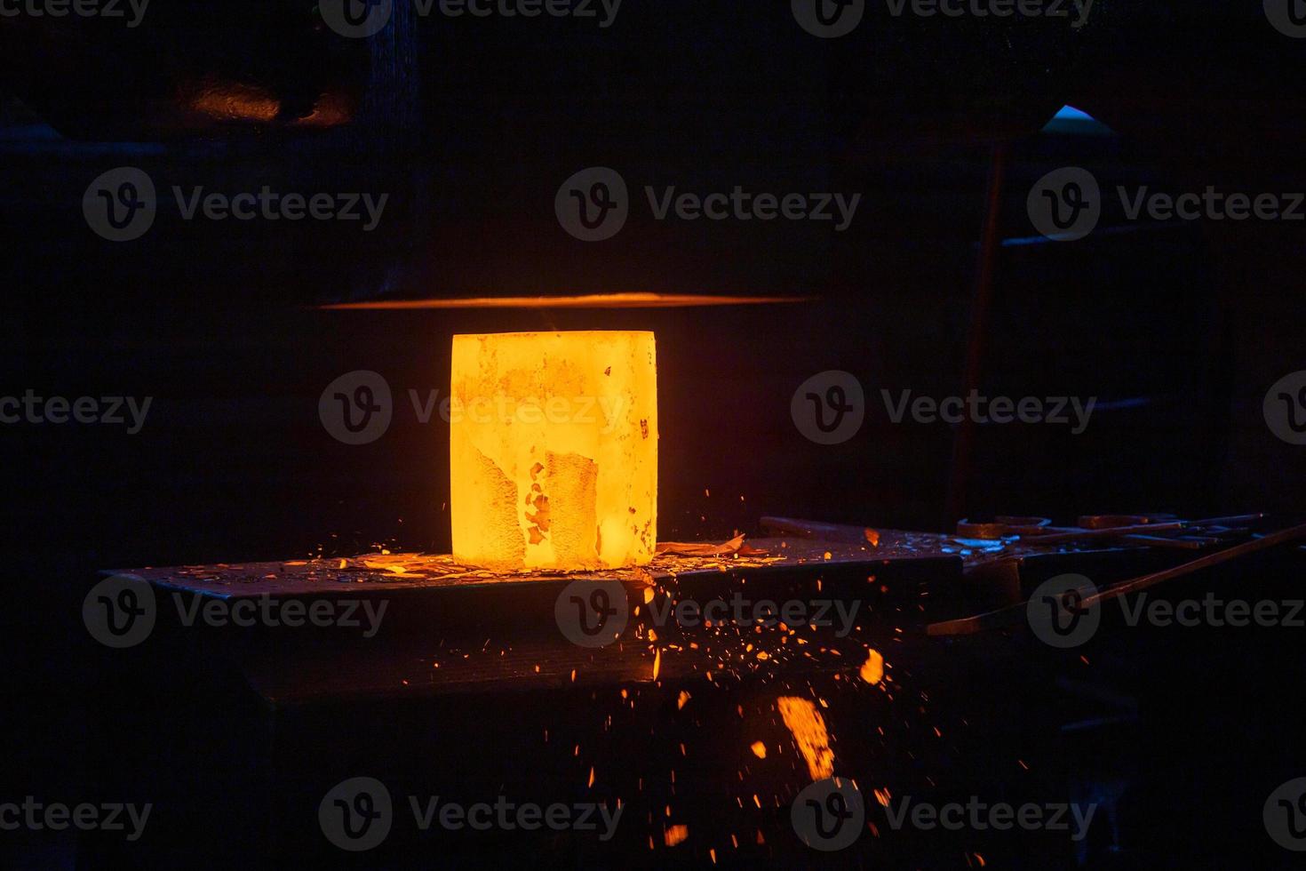 close-up picture of hot steel manual forging process with big mechanical hammer machine photo
