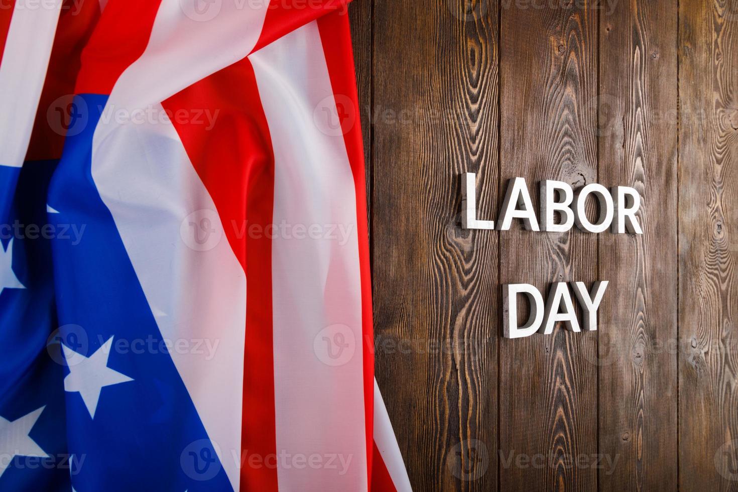 words labor day laid with silver metal letters on wooden surface with crumpled USA flag on left side photo