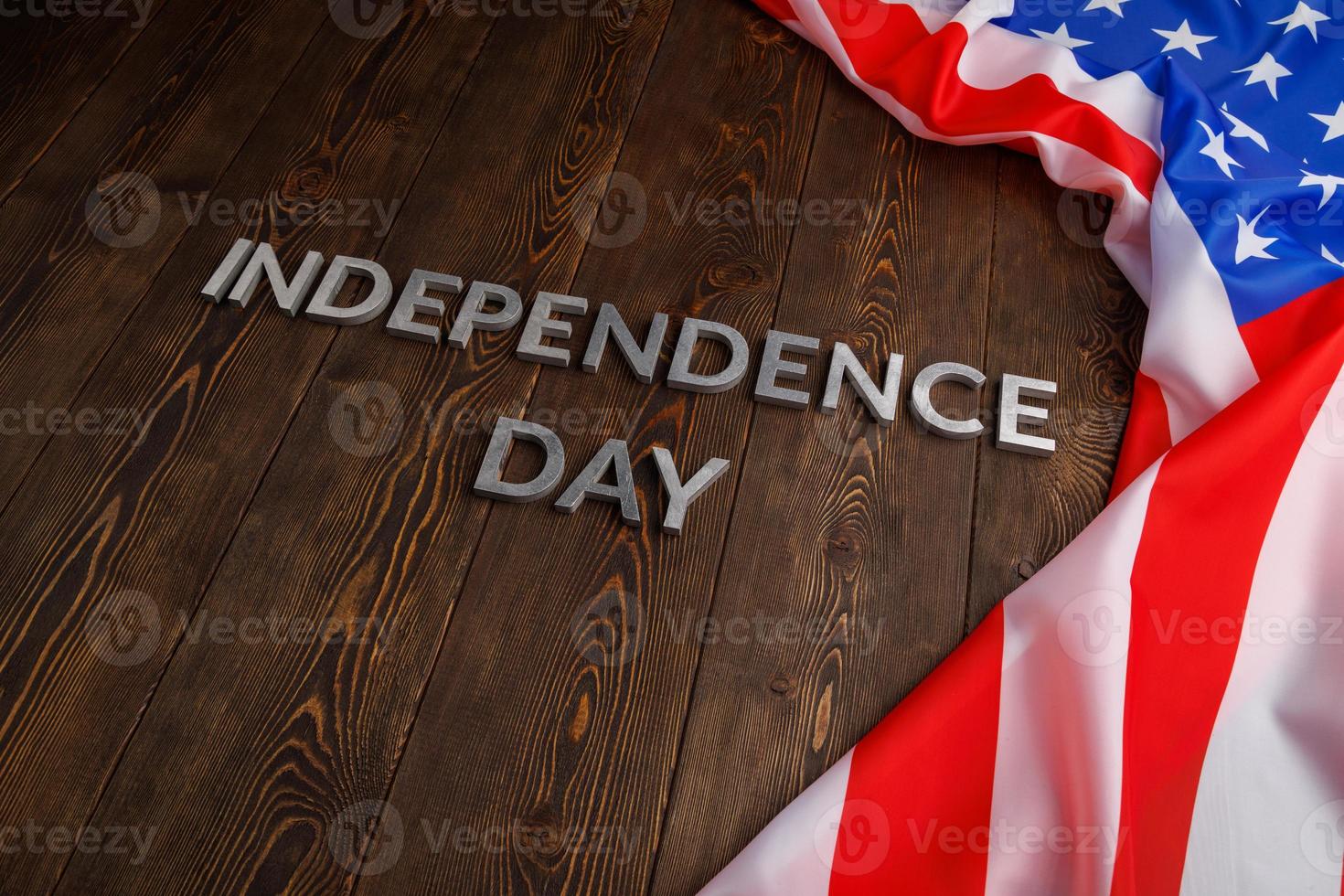 the words independence day laid on brown wooden planks surface with crumpled united states of america flag photo