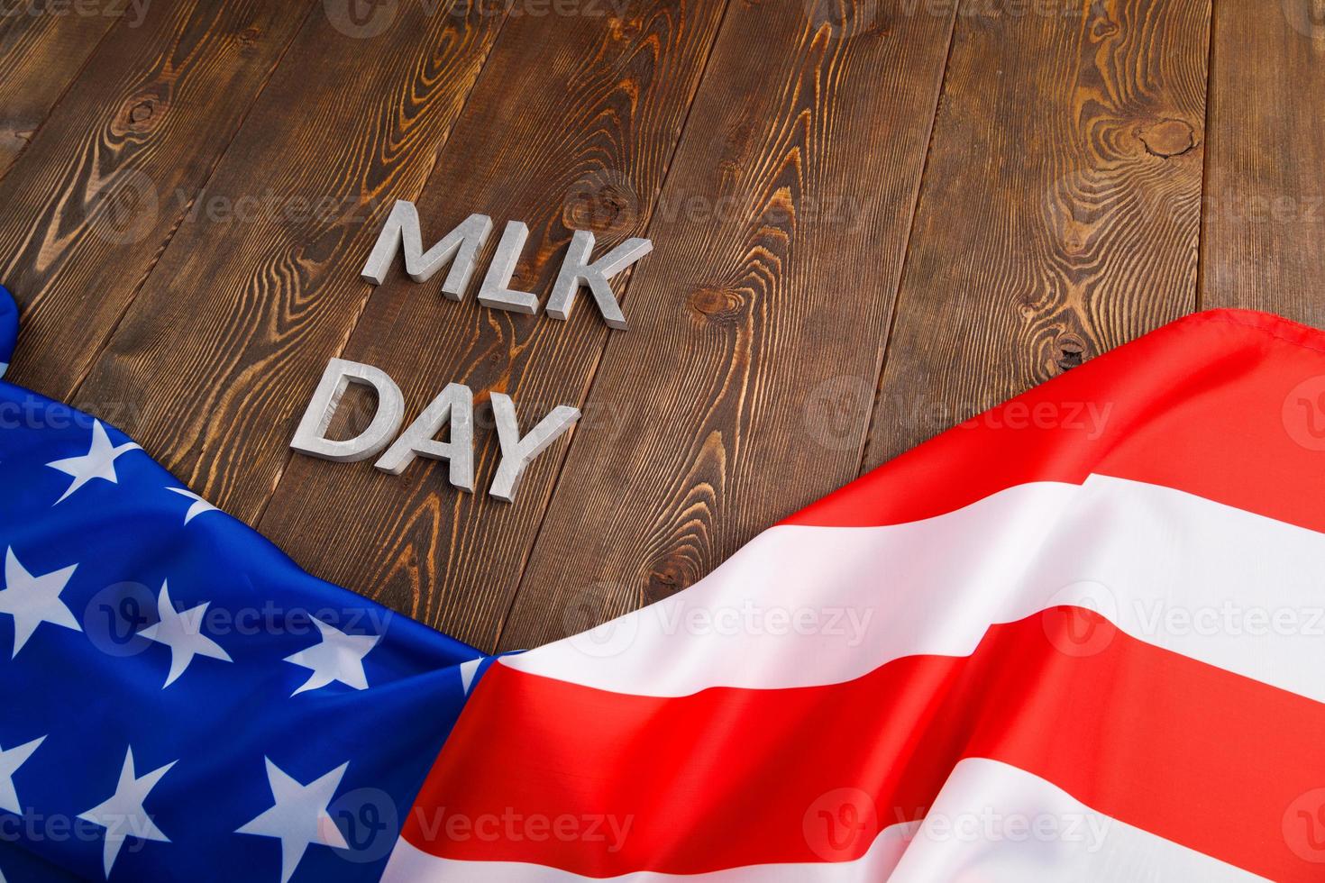 the word MLK day laid with silver metal letters on wooden surface with crumpled USA flag underneath photo
