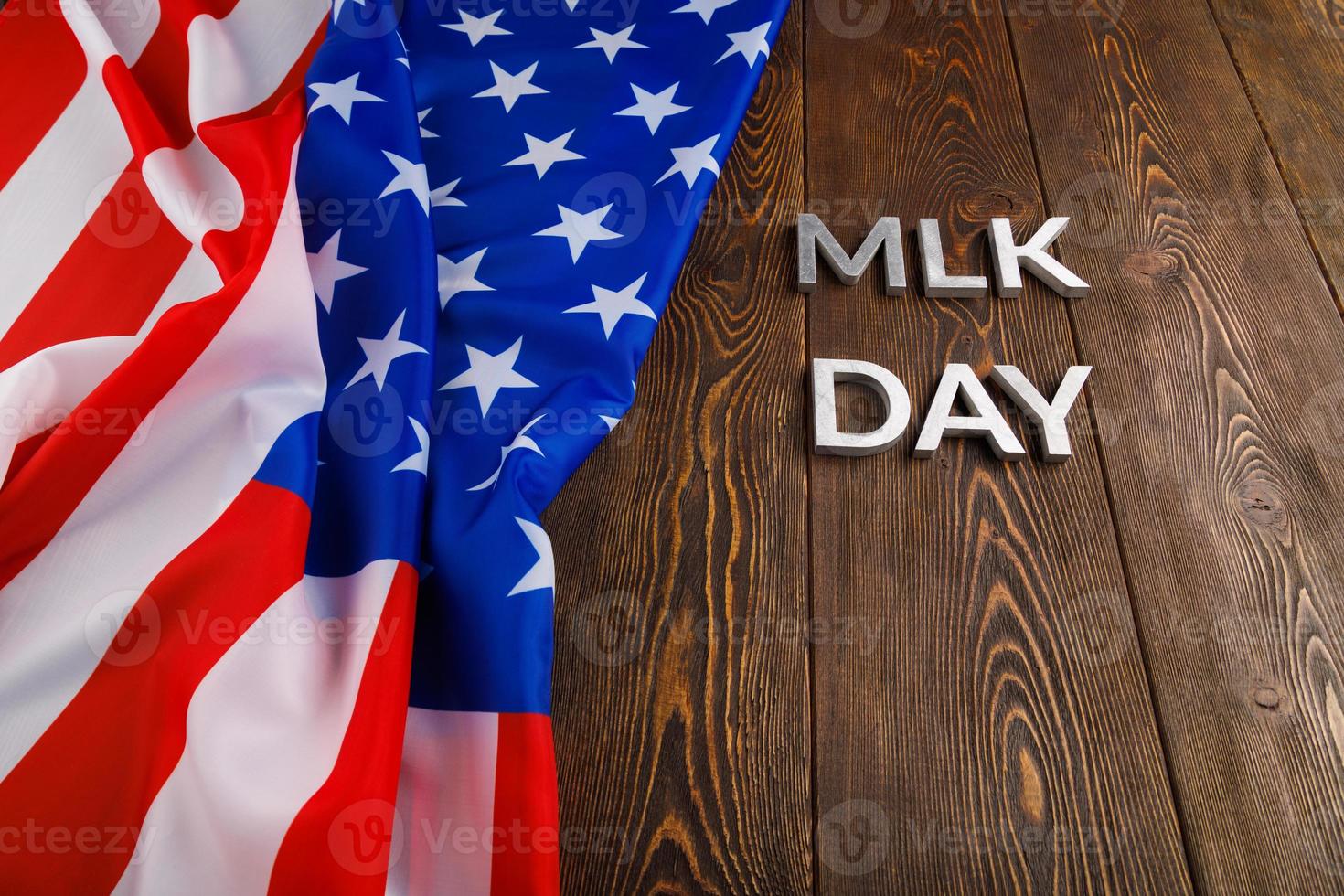 the word MLK day laid with silver metal letters on wooden surface with crumpled USA flag photo