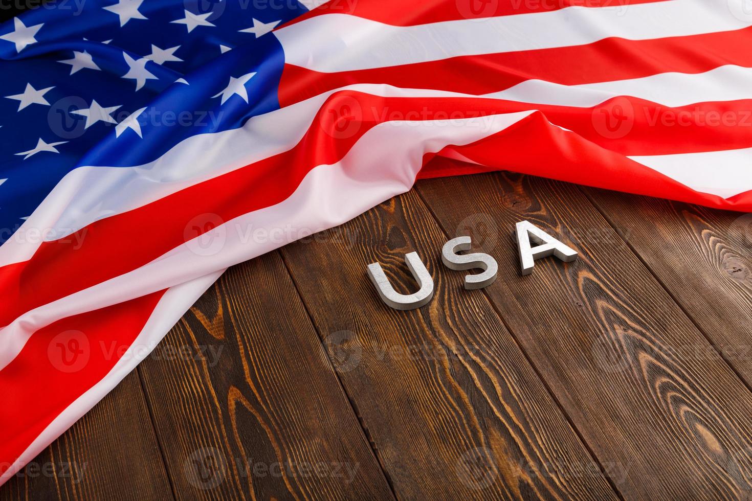 bandera de los estados unidos de américa arrugada y con la palabra usa colocada sobre un fondo de superficie de madera con textura plana foto