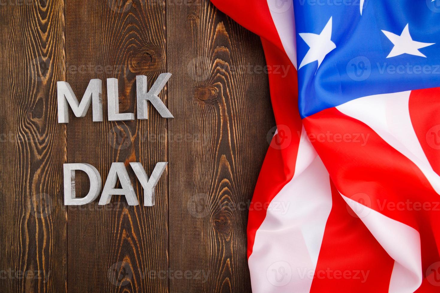 the word MLK day laid with silver metal letters on wooden surface with crumpled USA flag at right side photo