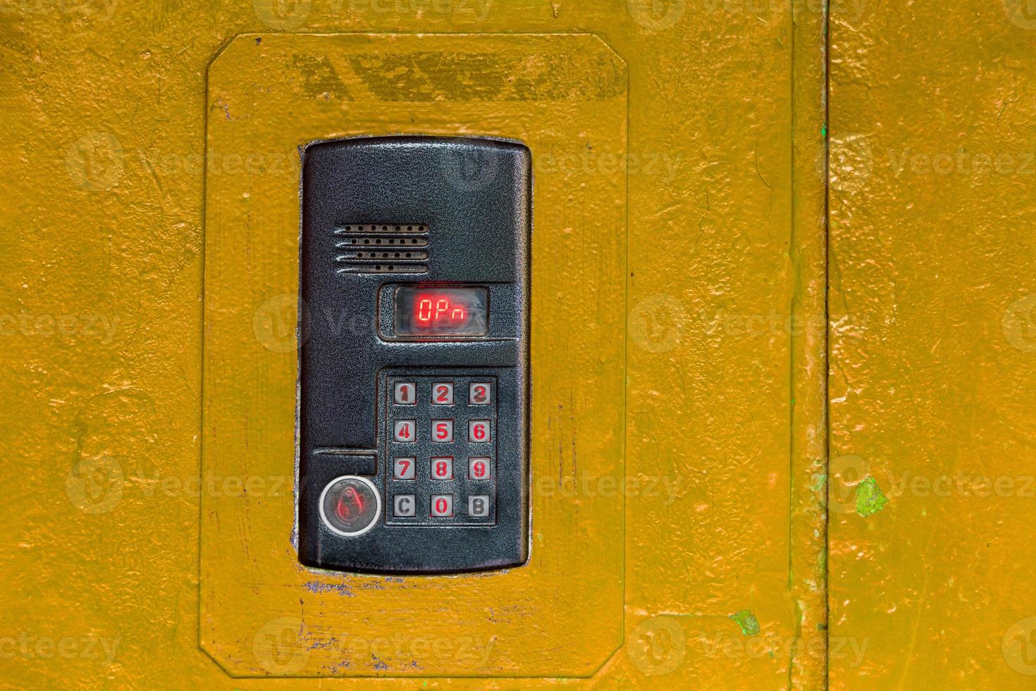 An intercom on old painted yellow steel surface with a keypad, digital display and rfid sensor for calling close-up photo