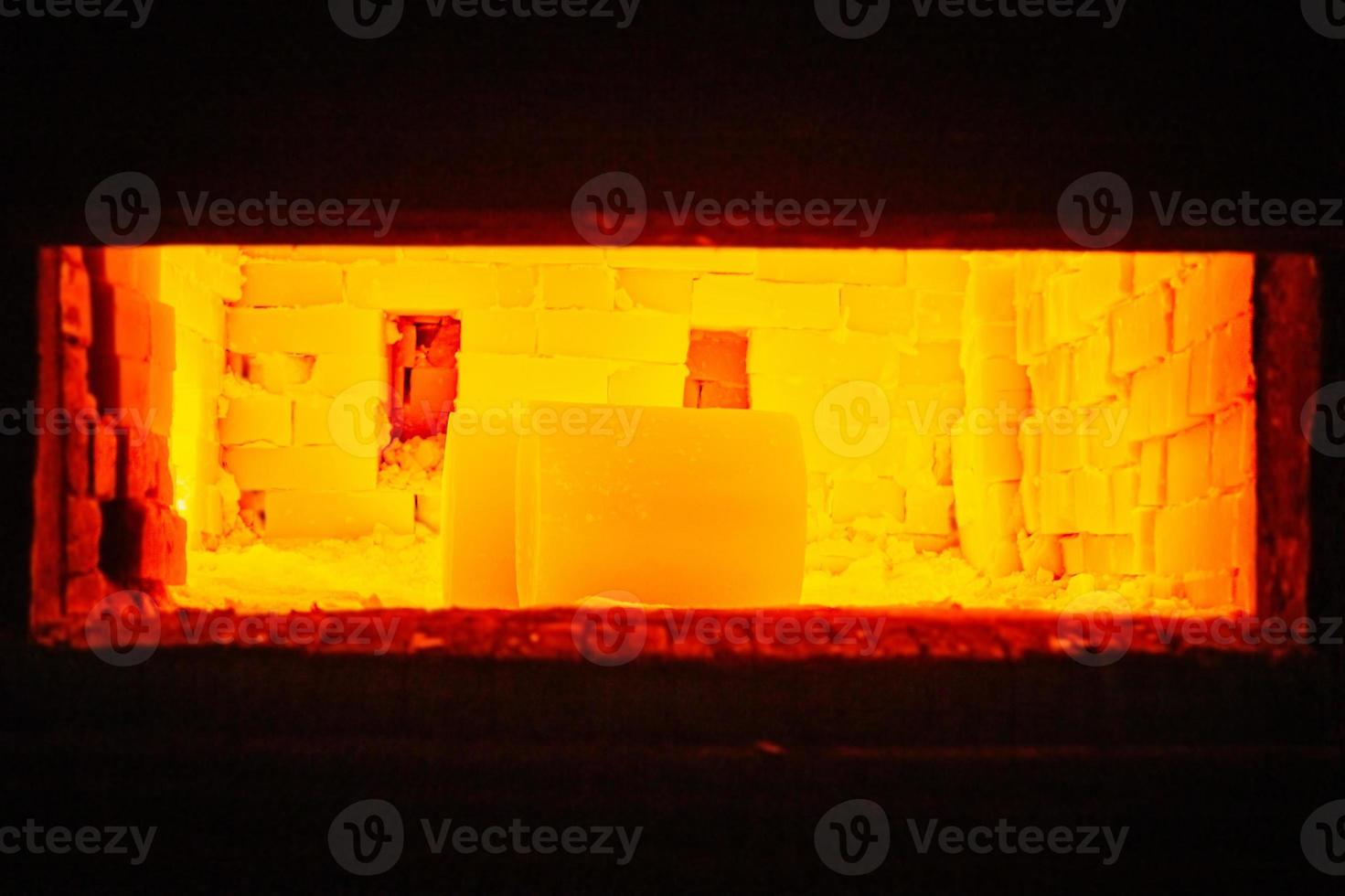 un par de piezas de trabajo cilíndricas brillantes de color amarillo caliente pesado que se calientan dentro del horno de gas foto