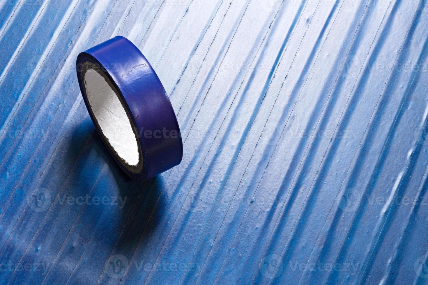 one roll of old blue pvc duct tape on ti's self flat background photo
