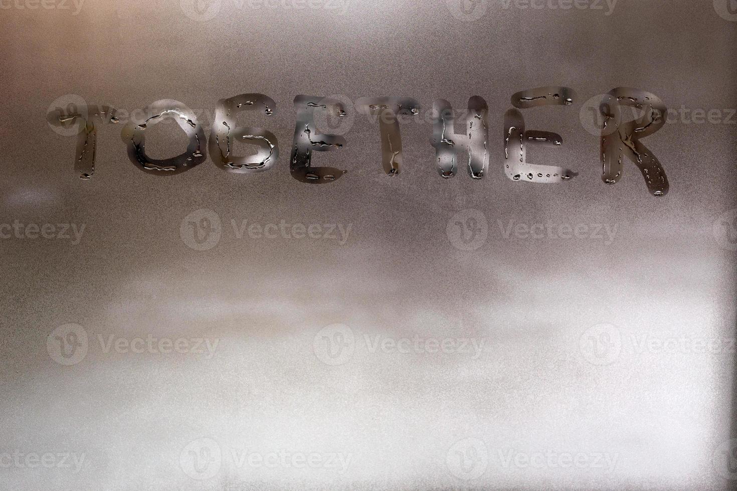 the word together handwritten on wet window glass at daytime - close-up full frame picture with selective focus photo