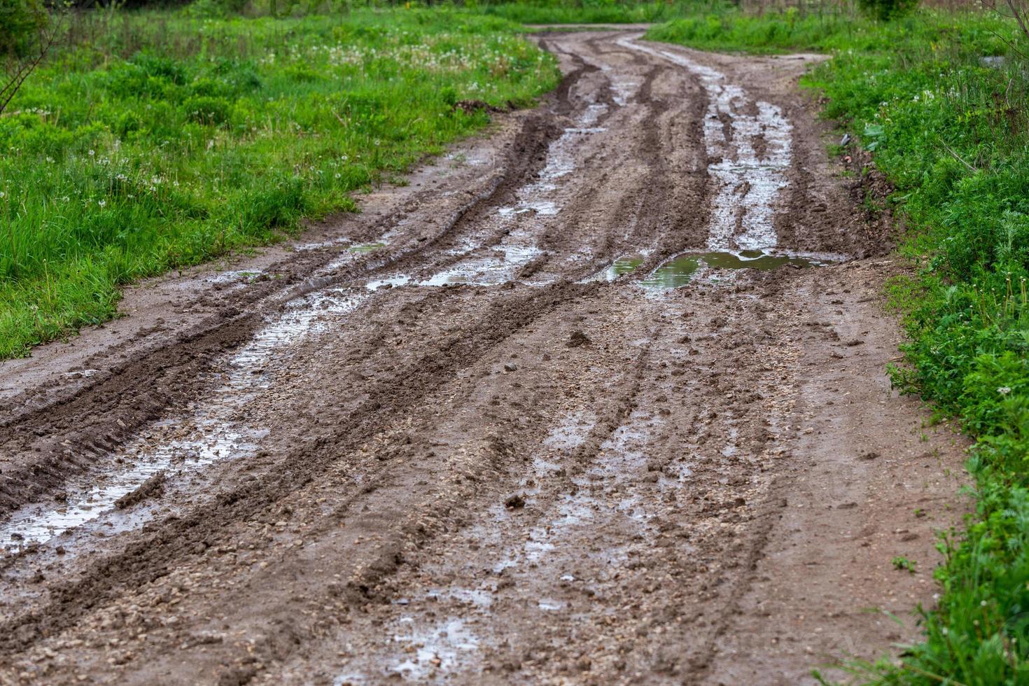 dirty road with puddles and tire tracks - closeup with selective focus photo