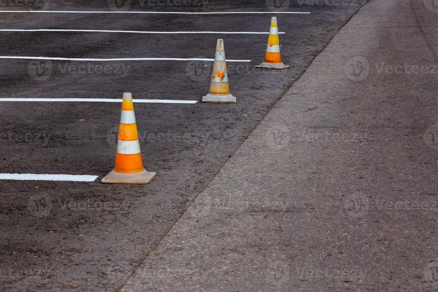 Orange road cones on a asphelt driving area with white lines photo