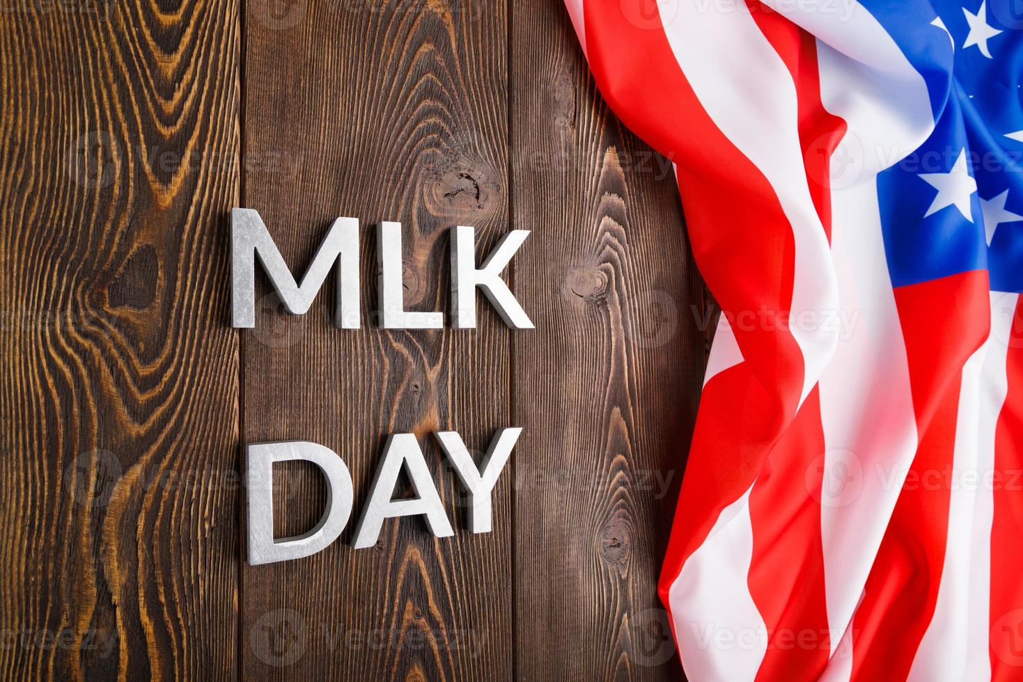 the word MLK day laid with silver metal letters on wooden surface with crumpled USA flag at right side photo