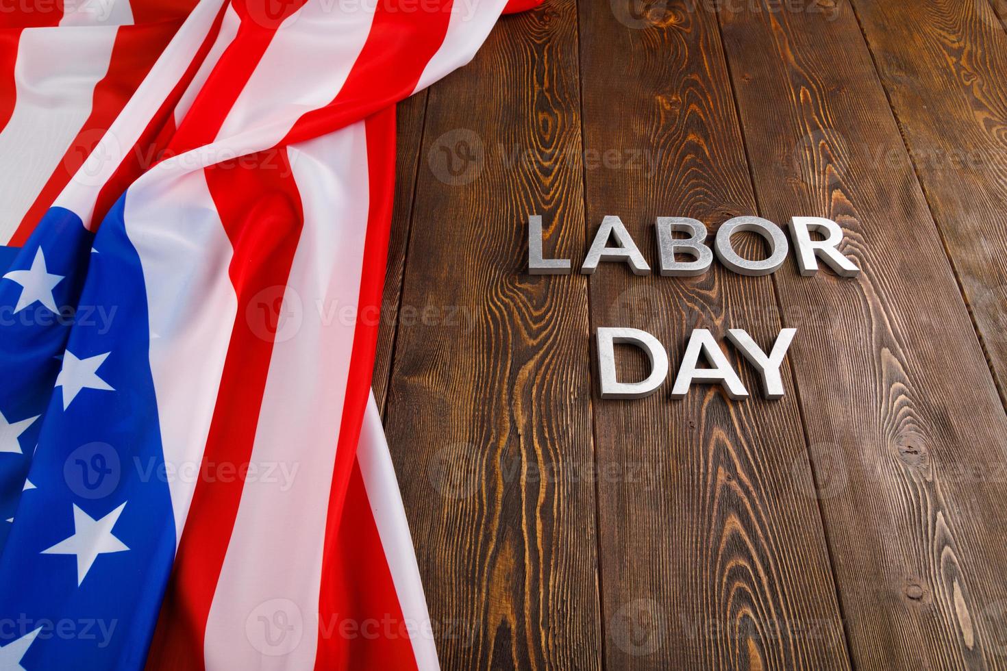 words labor day laid with silver metal letters on wooden surface with crumpled USA flag on left side photo