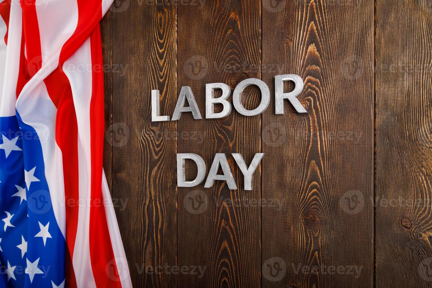 words labor day laid with metal letters on wooden surface with crumpled USA flag photo
