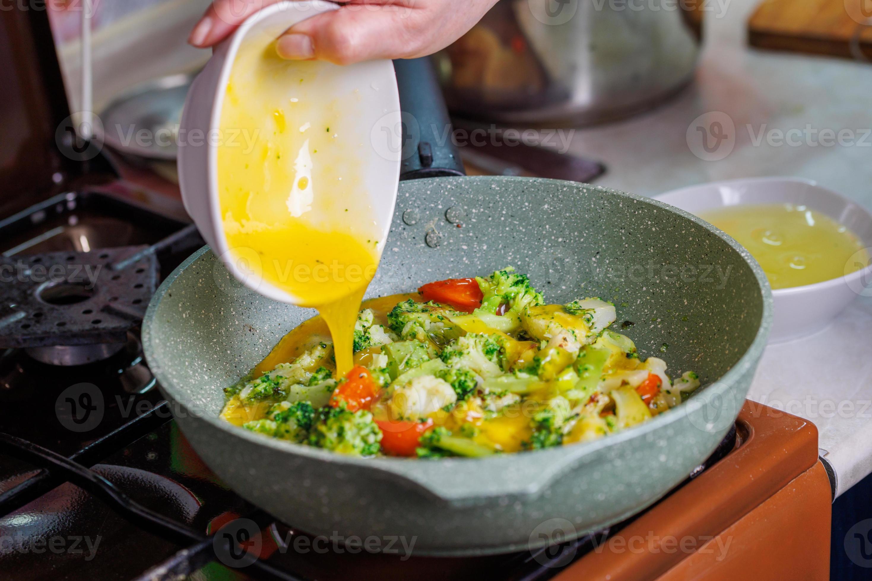 female hands adds a scrambled egg yolks to frying vegetables while