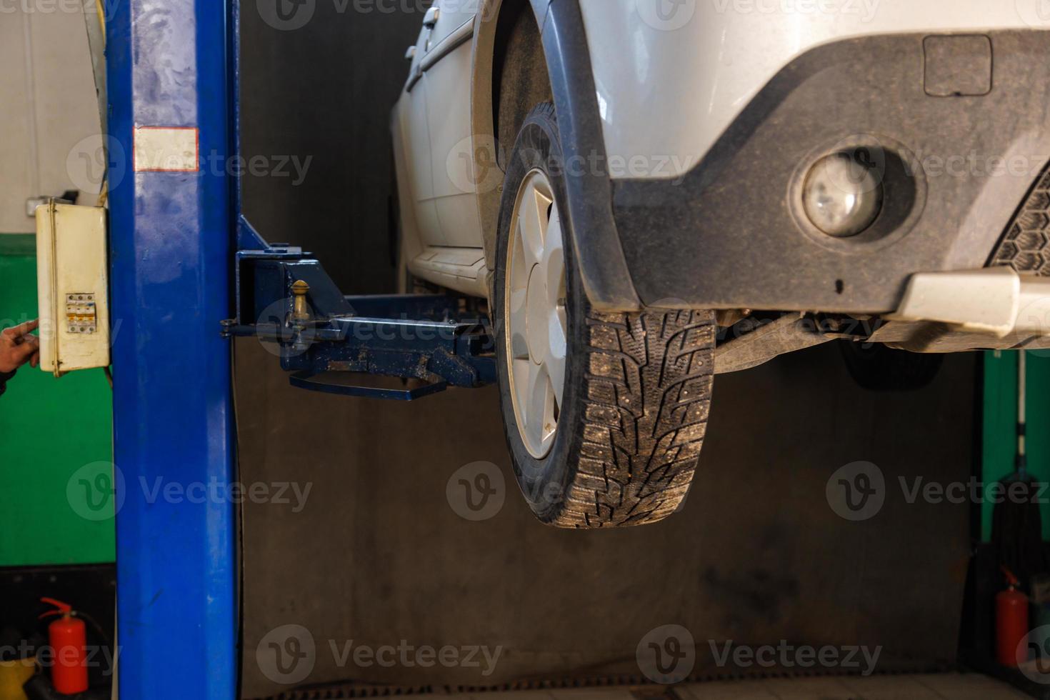 silver car lifted on elevator at maintenance in auto repair shop photo