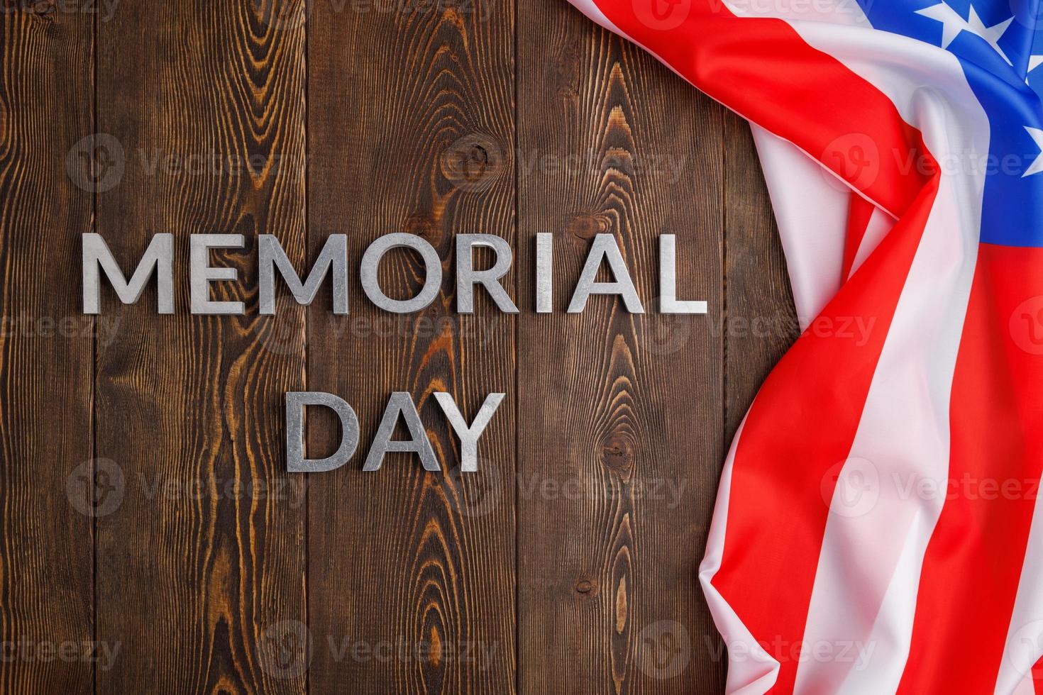 the words memorial day laid with silver metal letters on wooden board surface with crumpled usa flag photo