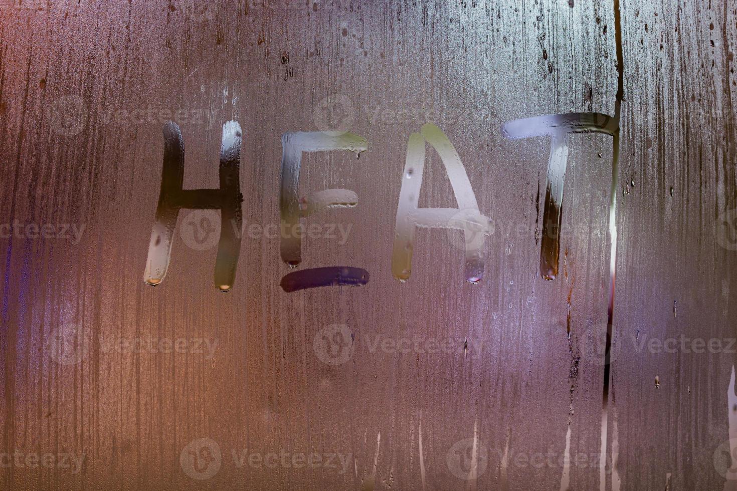 the word heat written on night wet window glass close-up with bokeh background photo