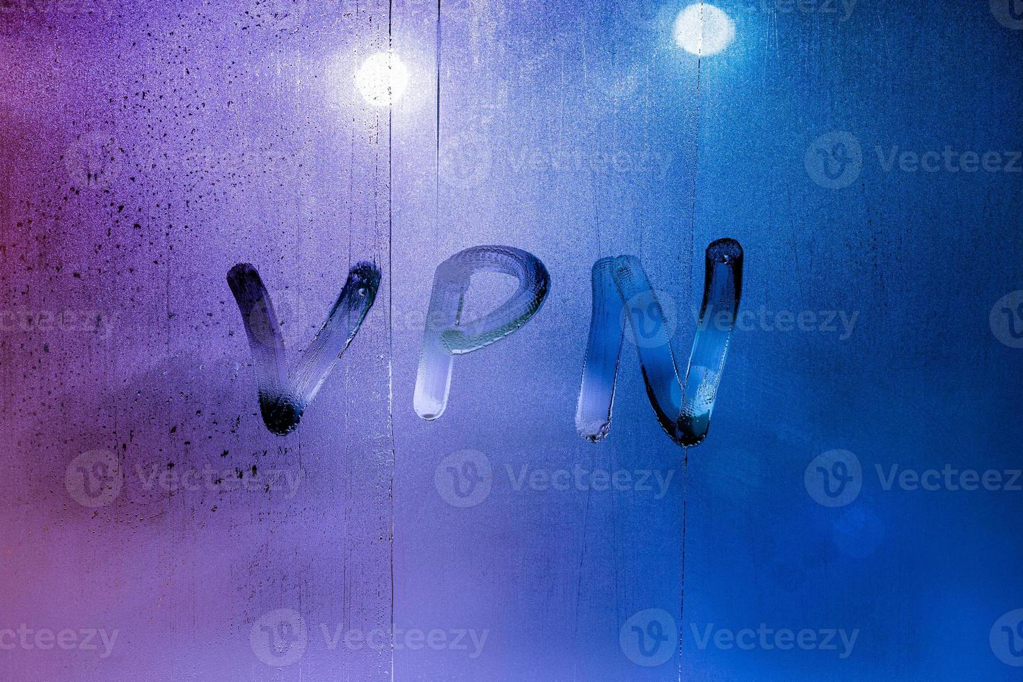 una abreviatura vpn - red privada virtual dibujada con el dedo en el vidrio húmedo nocturno foto