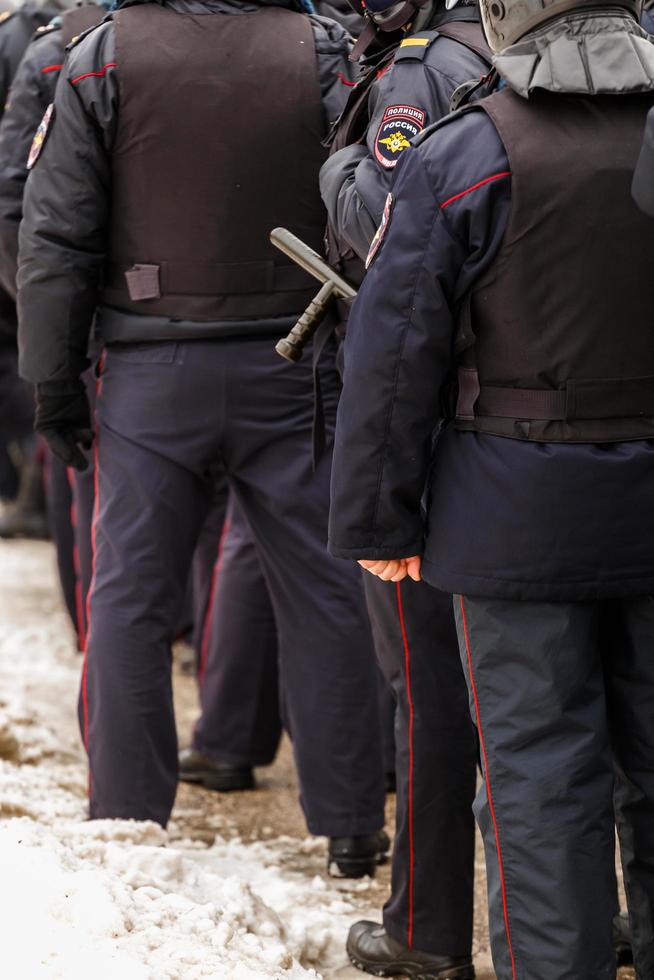 TULA, RUSSIA  JANUARY 23, 2021 Crowd of police officers in black uniform with bulletproof vests and pistols - view from back. photo