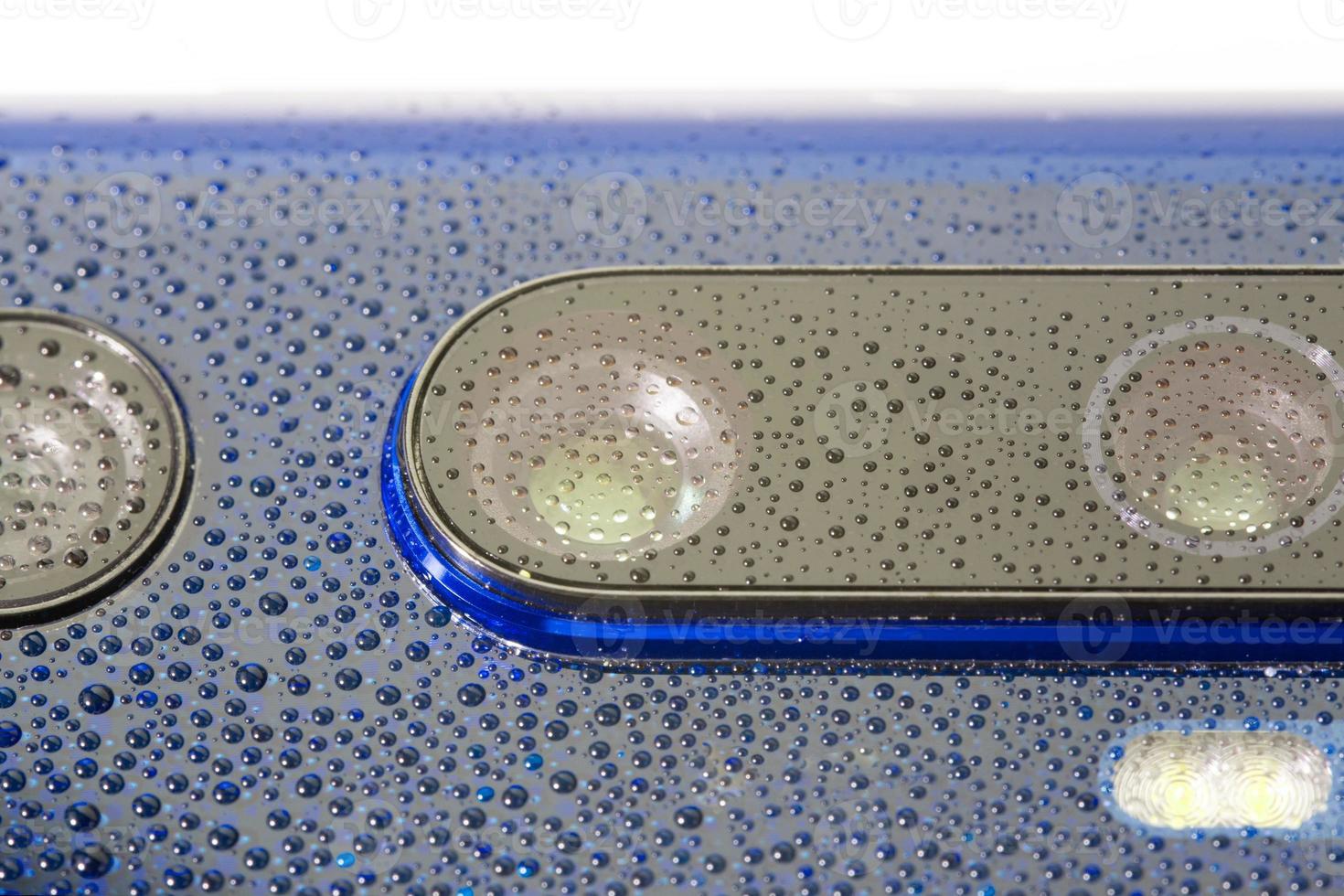 blue phone camera lens covered with small water drops - close-up with selective focus and blur photo