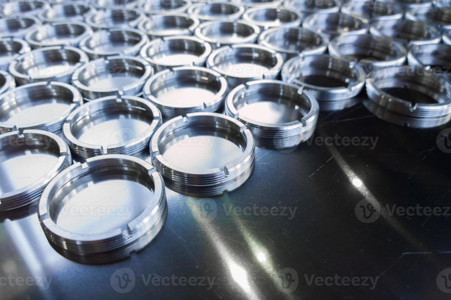 shiny metal rings after turning and milling, silver colored parts on flat steel surface close-up full frame background photo