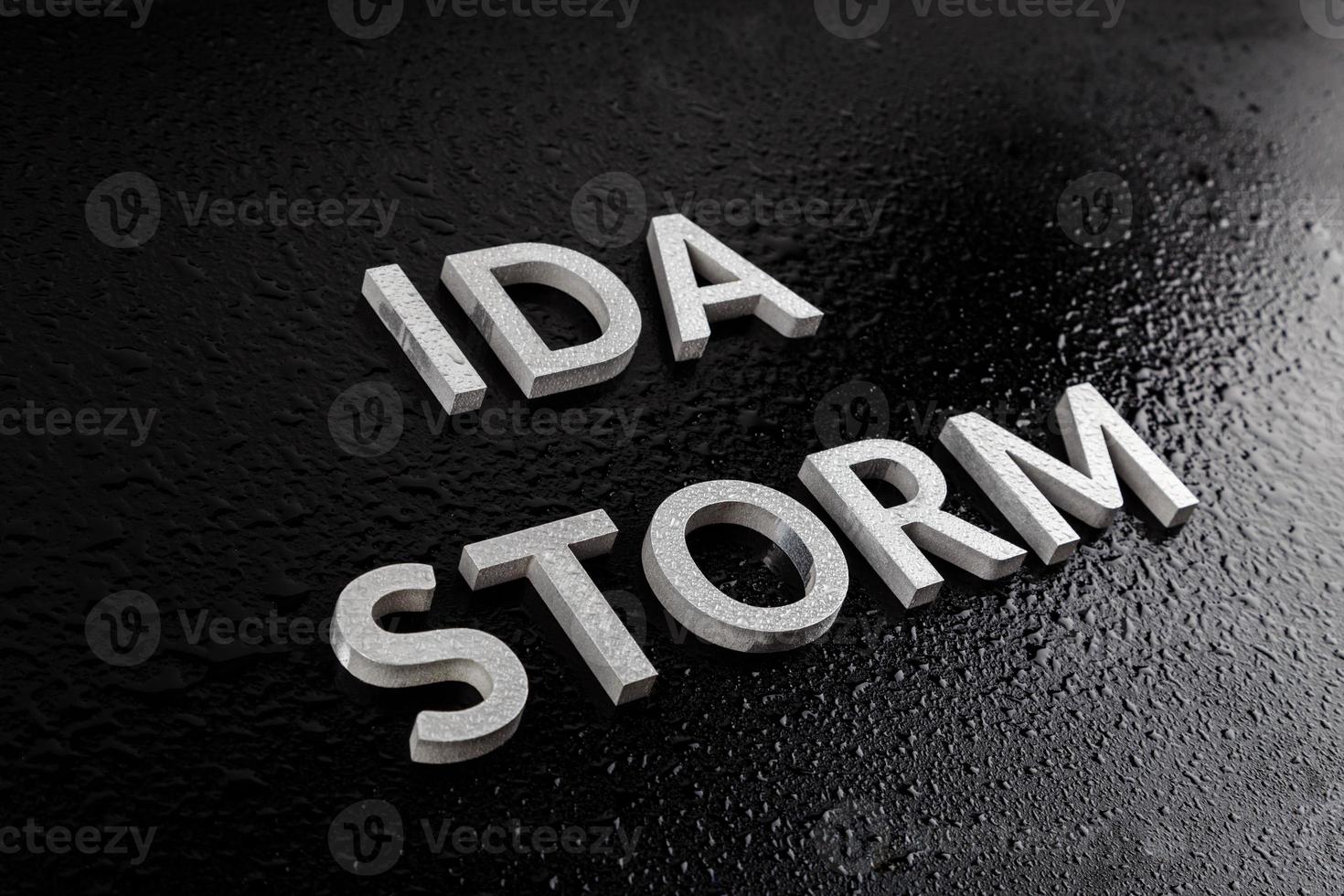 the words ida storm laid with silver metal letters over black surface both covered with rain water drops photo