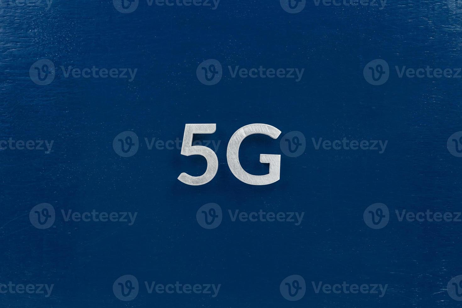 the word 5G laid with aluminium letters on dark blue background photo