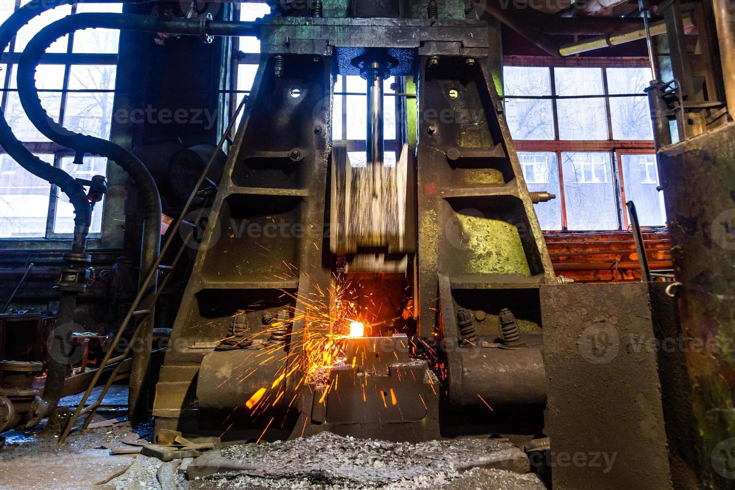 old working steam hammer at factory forging hot steel workpiece with sparks photo