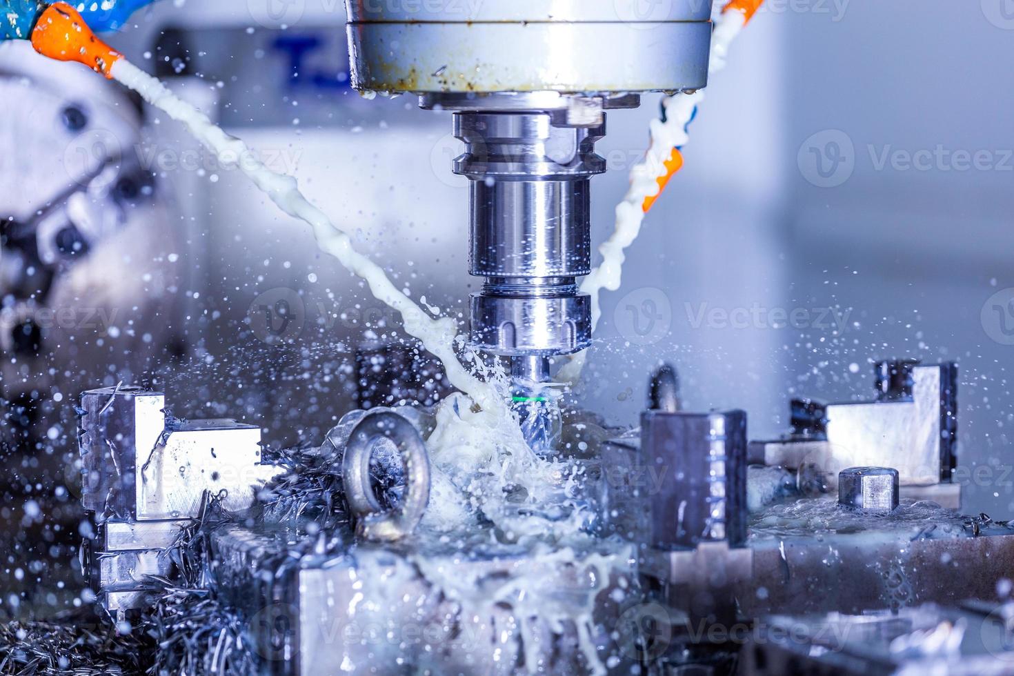 vertical cnc steel milling process with external water coolant streams, splashes and a lot of metal chips, high contrast photo