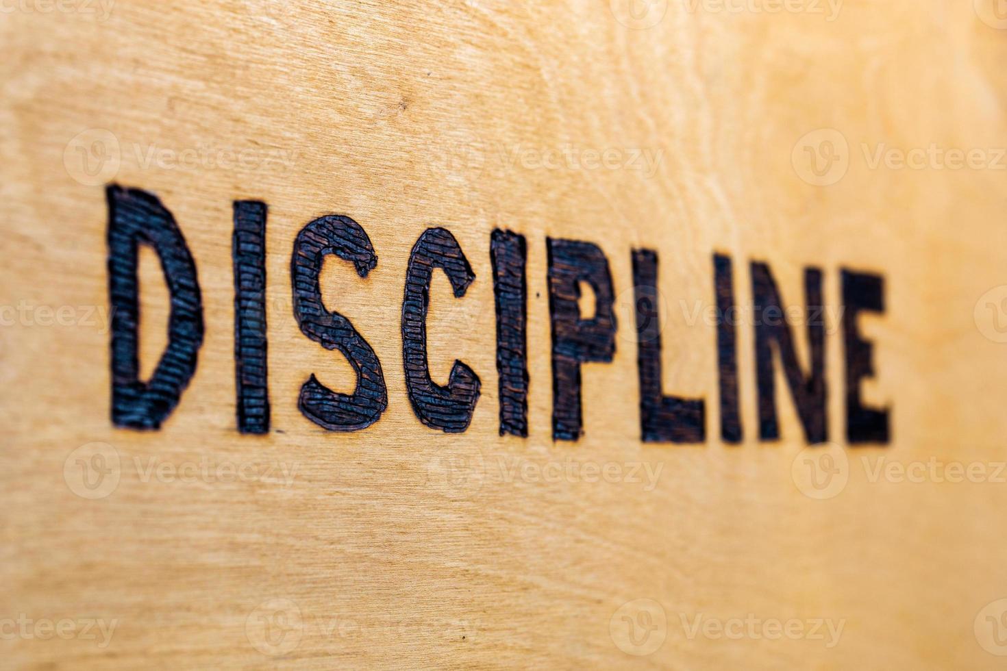 the word discipline burnt on white flat wooden surface perspective