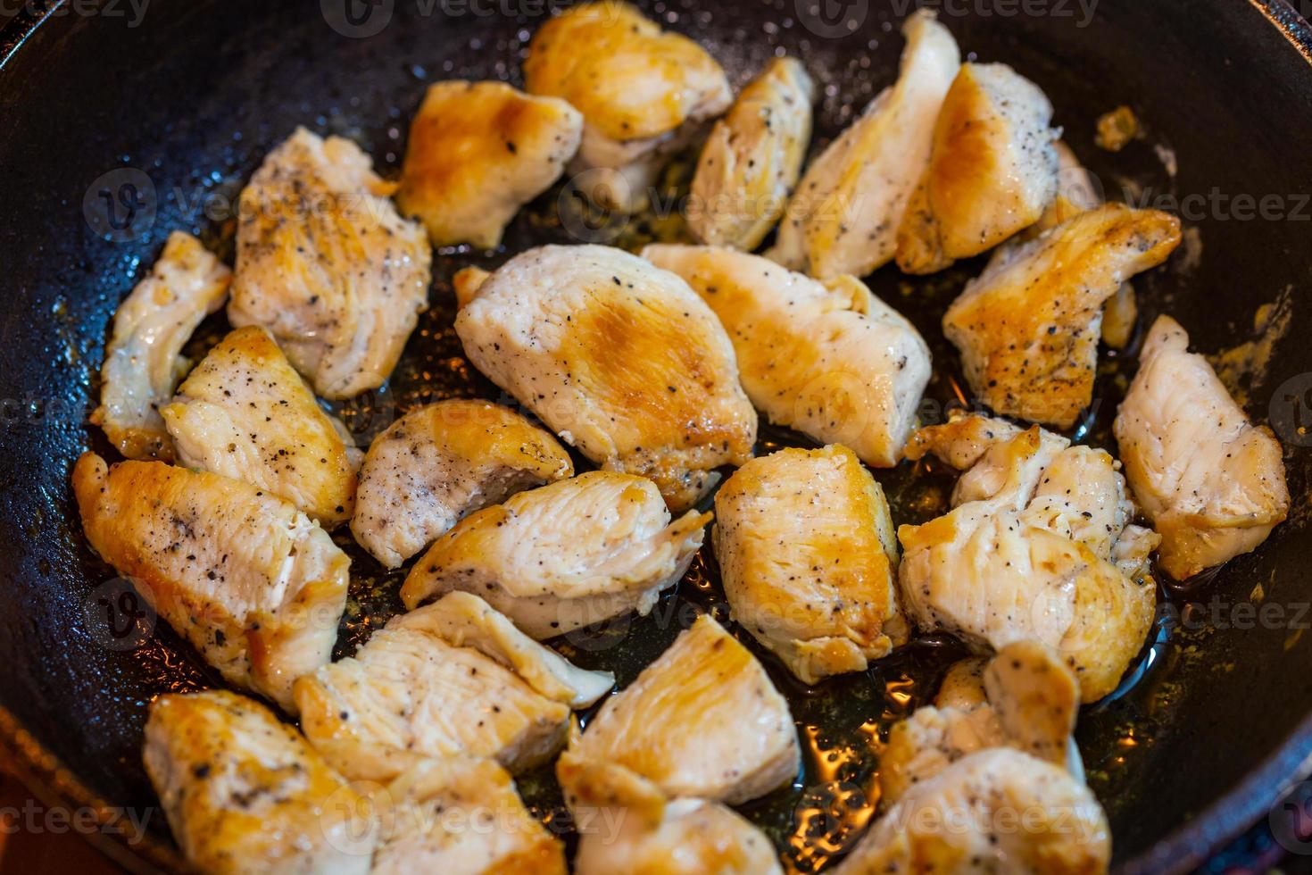 fried chicken in a pan with ground black pepper photo
