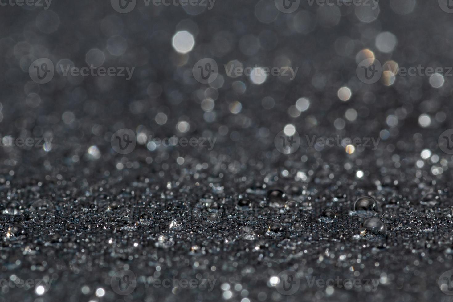 dark grey water resistant hydrophobic flat cloth with rain drops, close-up background with selective focus photo