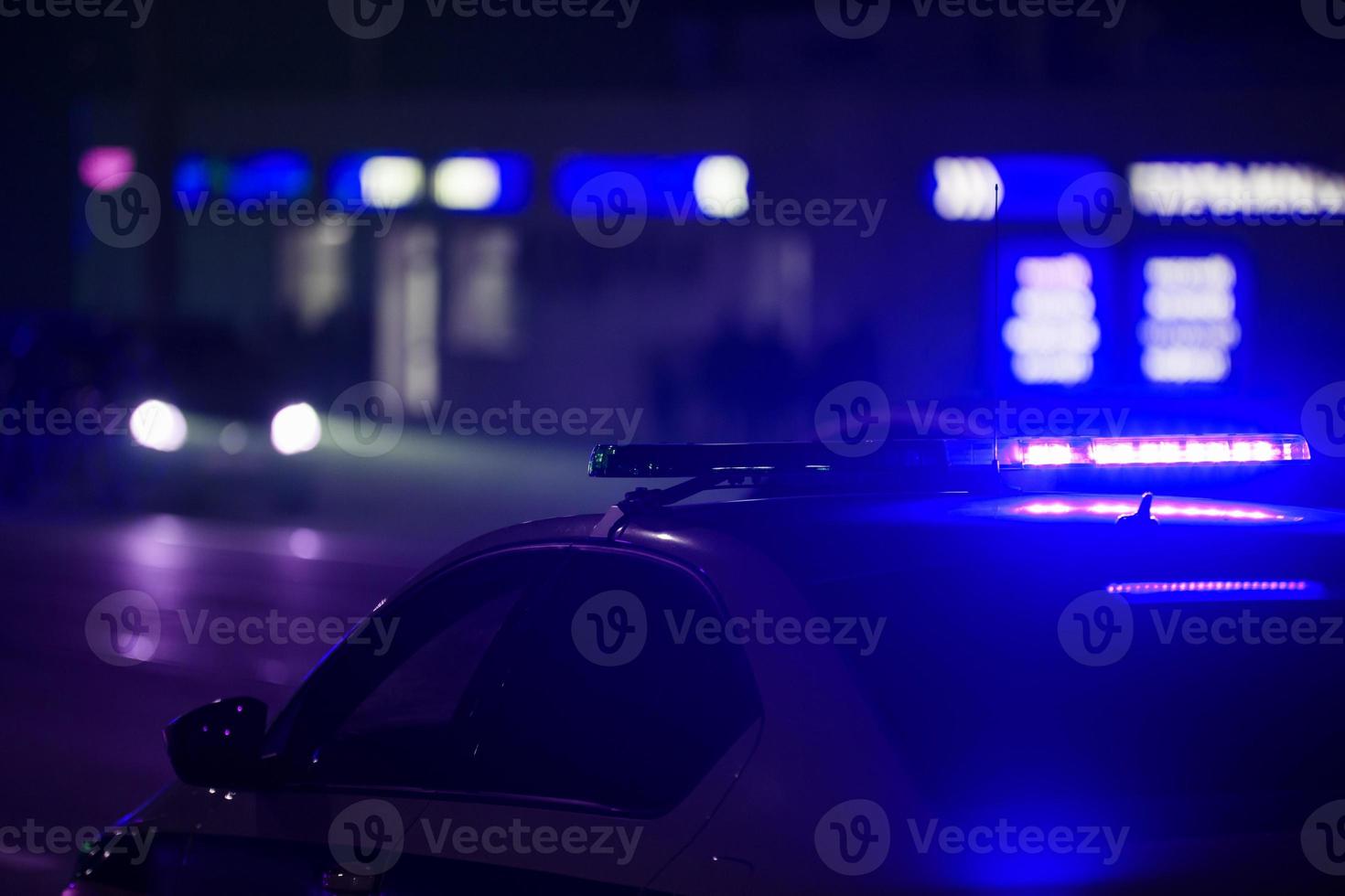 blue police car light at night in city with selective focus and bokeh on black background photo