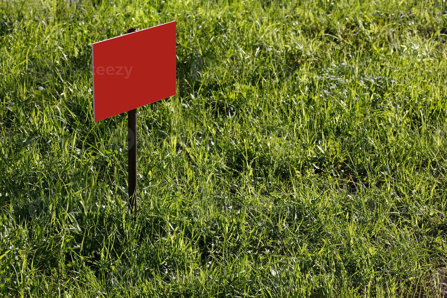 blank red sign mockup on green lawn background - close-up with selective focus photo
