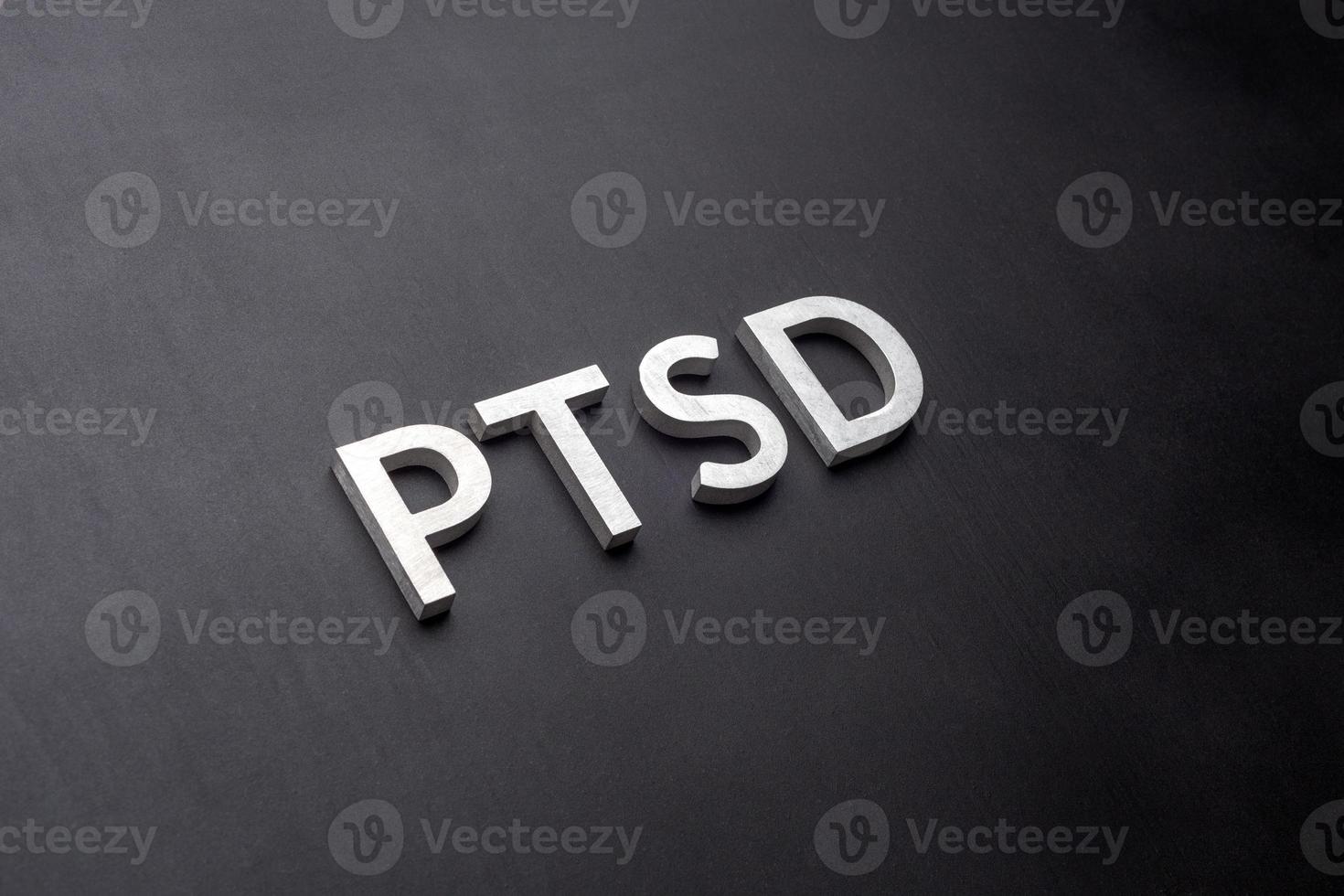 the word PTSD laid with silver metal letters on flat black background in linear perspective photo