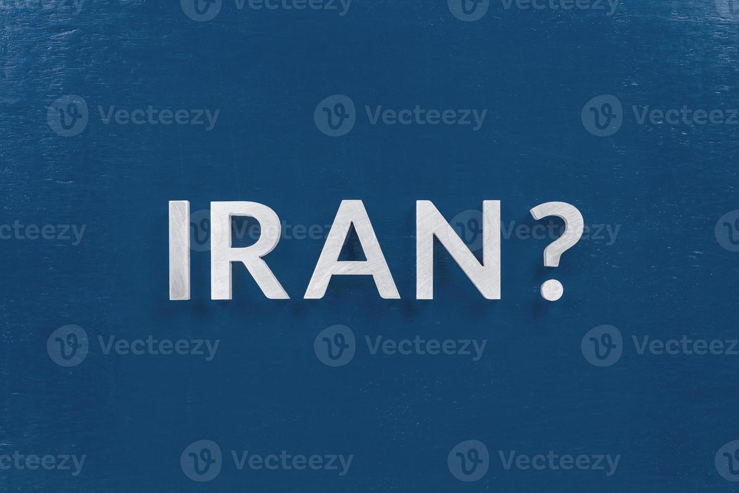 a question iran laid with silver metal letters on classic blue board in flat lay with central composition photo