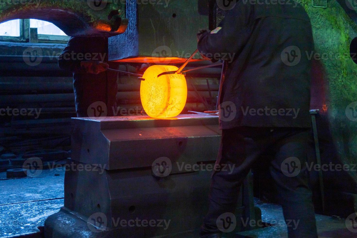 close-up picture of hot steel free forging process with big mechanical hammer machine photo